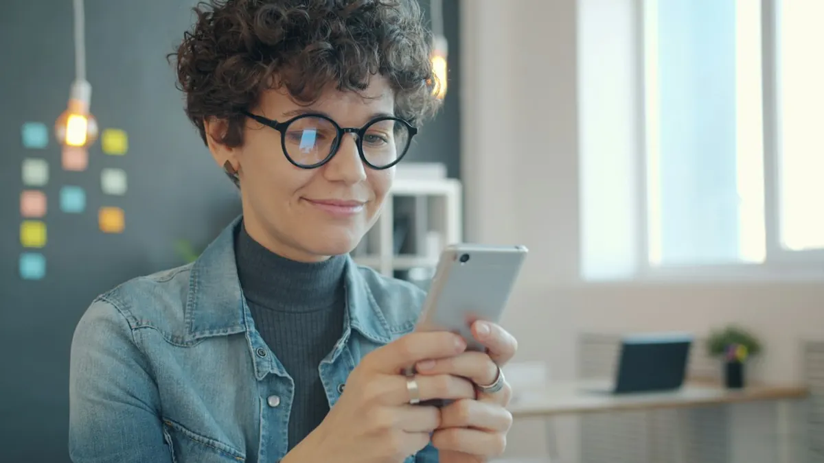 Mulher sorrindo olhando o celular