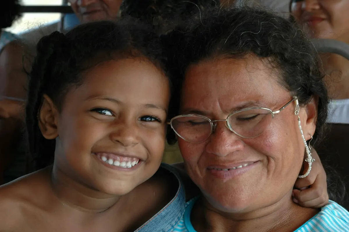 Mulher sorrindo abraçada a uma criança